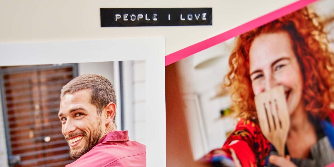 Su un frigorifero sono appese due foto stampate. A sinistra si vede un ragazzo, a destra una ragazza che tiene in mano un mestolo. Sopra le due foto c'è la scritta "people I love" creata con l'etichettatrice.