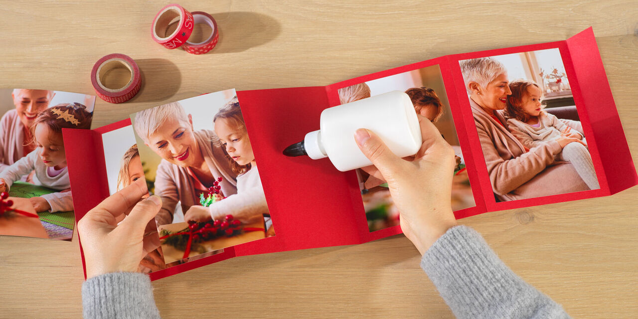 Due mani attaccano le foto di un bambino con la nonna su uno sfondo rosso.