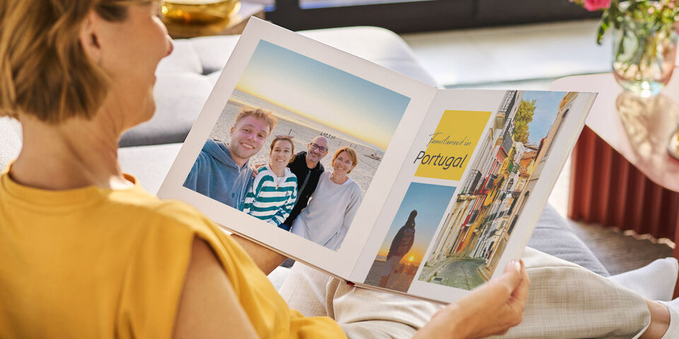 Eine Person betrachtet ein CEWE Fotobuch mit Urlaubsfotos aus Portugal.